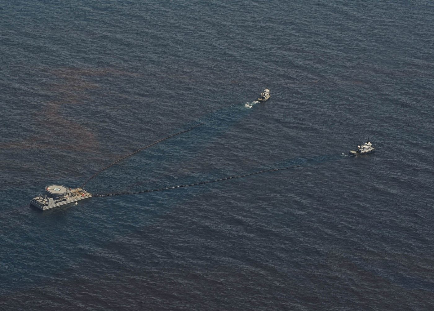 Foto udara: dua kapal menarik oil boom berbentuk V ke arah kapal penampung di tengah lapisan minyak, Teluk Meksiko 2010